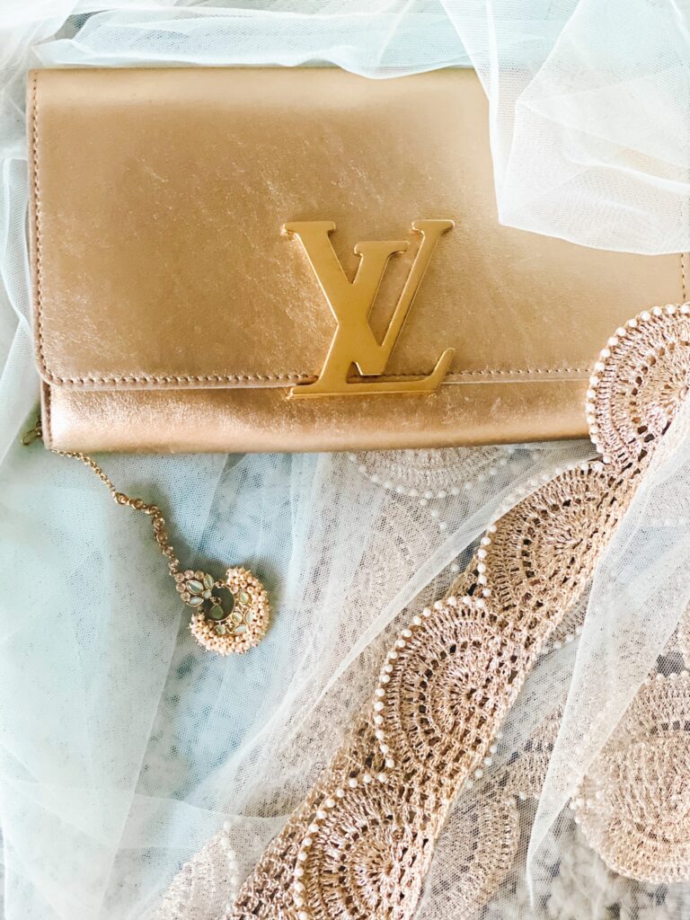 Louis Vuitton clutch on top of green scarf