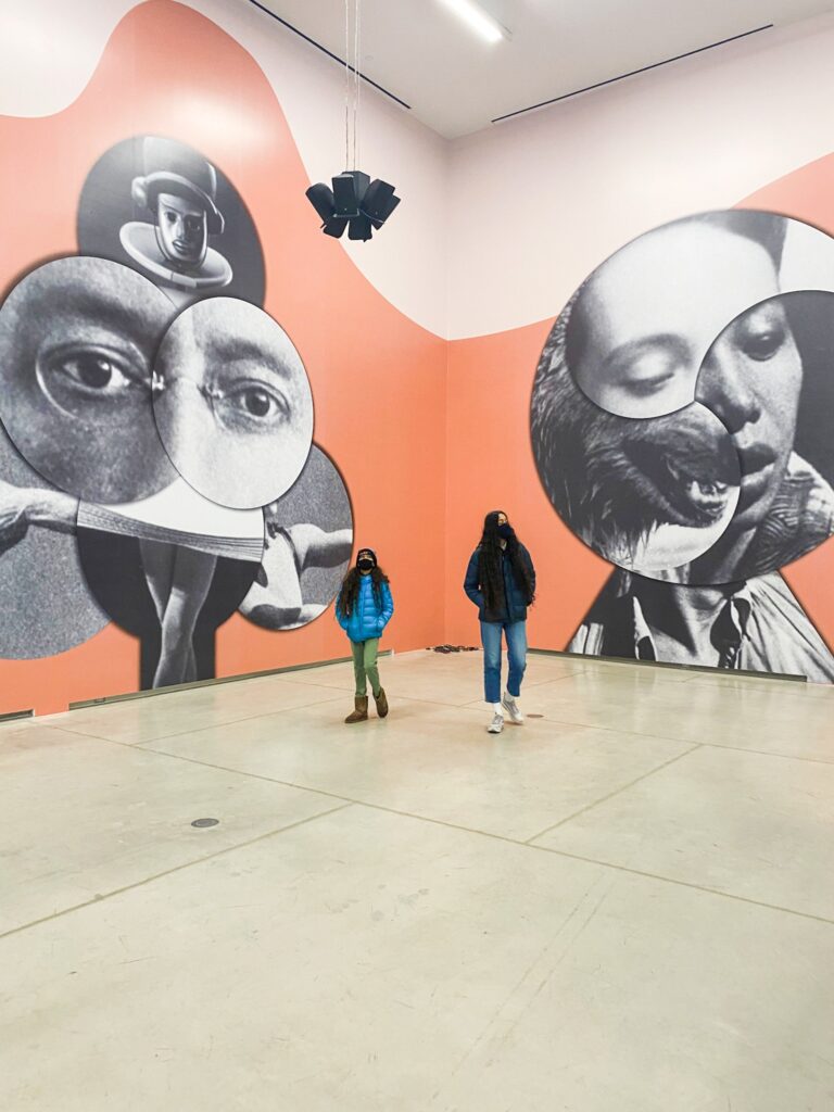 Two kids walking in a large room filled with murals
