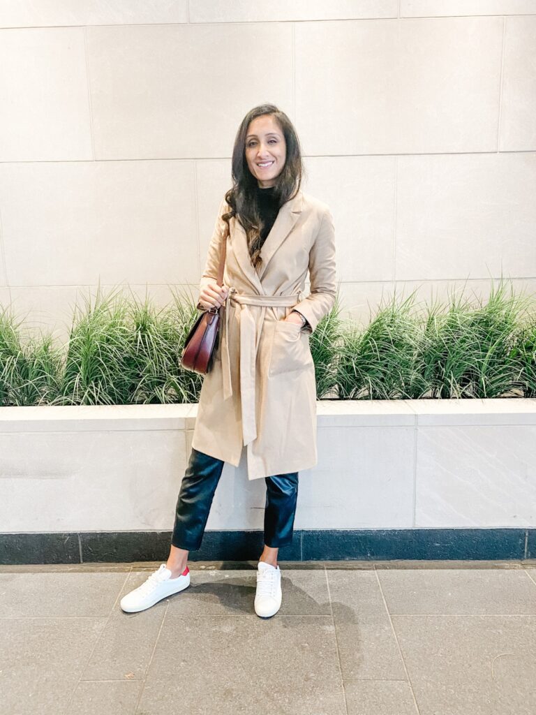 Standing in a beige coat and sneakers